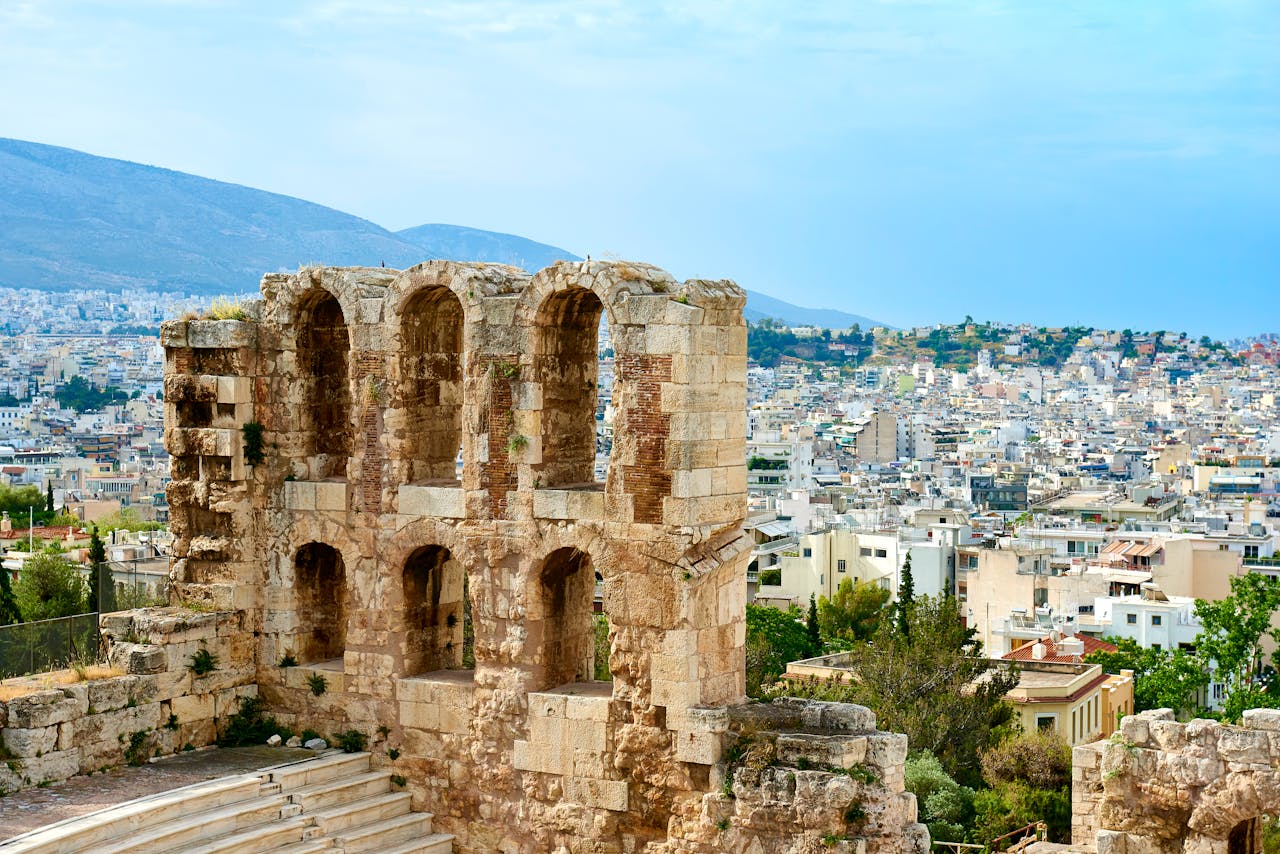 The iconic Odeon of Herodes Atticus in Athens with the city skyline and mountains in the background.